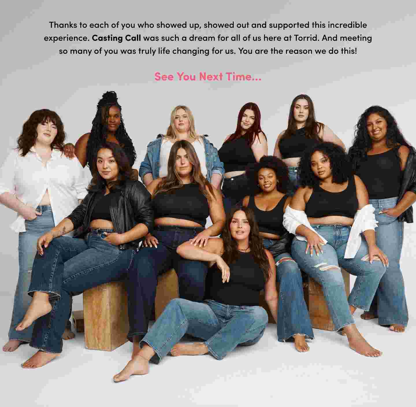 A group photo featuring a diverse group of 12 women, all confidently posing together in a studio setting. The women are wearing a mix of black crop tops, denim jeans, and some are accessorized with denim jackets or white tops. They are seated or standing on and around wooden blocks, creating a relaxed and supportive atmosphere. The text above the group expresses gratitude to those who participated in and supported the Torrid Casting Call, calling it a life-changing experience and ending with See You Next Time in pink text. The background is a simple gray, keeping the focus on the group.