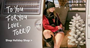 
A young woman is sitting in the open doorway of a van dressed in cozy winter clothing including a knit hat scarf and sweater with a relaxed and cheerful expression Next to her is a small artificial Christmas tree The text overlay reads To You For You Love Torrid with a prompt below saying Shop Holiday Shop The scene evokes a festive holiday shopping theme in a casual outdoor setting