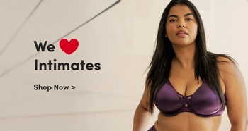 A woman modeling a purple lingerie set, featuring a satin bra with crisscross details. She stands confidently with a neutral background featuring soft lines. The text on the image reads: 'We ♥ Intimates. Shop Now >' in bold lettering