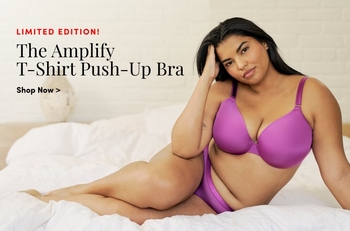 A woman modeling a purple lingerie set, featuring a satin bra with crisscross details. She stands confidently with a neutral background featuring soft lines. The text on the image reads: 'We ♥ Intimates. Shop Now >' in bold lettering