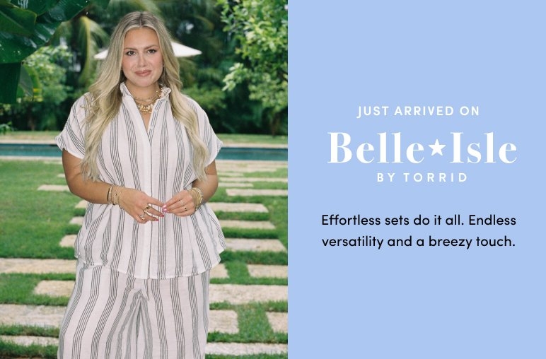 Smiling woman standing on a dock by the ocean wearing a white dress with blue floral prints and holding a straw hat. Text reads Just arrived on Belle Isle by Torrid. New dresses for your favorite season. So pretty. So airy. Made for sun