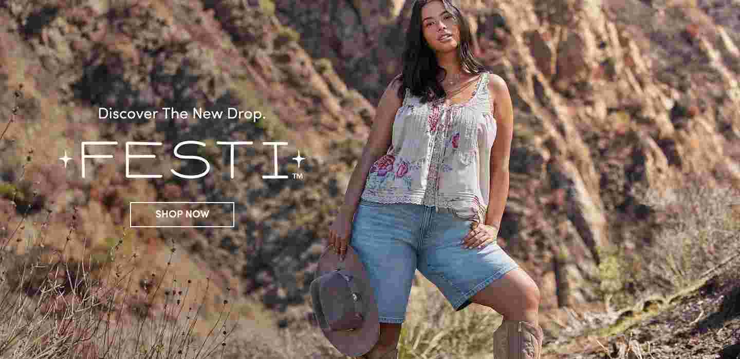 Woman standing confidently in front of rocky cliffs wearing a floral embroidered tank top, denim shorts, and holding a cowboy hat. Text reads Discover the New Drop FESTI with a Shop Now button.