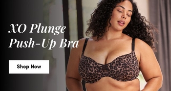 Woman wearing a leopard print XO Plunge Push-Up Bra with black straps, standing in a softly lit room with “Shop Now” button on the left.