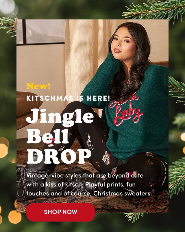 'Holiday promo image with pine branches and warm light bokeh framing a woman sitting indoors wearing black leggings printed with candy canes, stockings, and skulls, black snow boots, and a dark green fuzzy sweater with red embroidered text that reads Santa Baby. White and yellow text on the left reads New! KITSCHMAS IS HERE! Jingle Bell DROP. Below in smaller white text: Vintage-vibe styles that are beyond cute with a kiss of kitsch. Playful prints, fun touches and of course, Christmas sweaters. At the bottom is a red rectangular button with white text that reads SHOP NOW.'