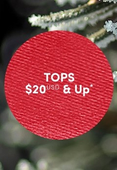 'Red circular badge with a fine fabric-like textured surface and white centered text that reads TOPS $20 USD & Up*, placed over a softly blurred dark green and gray background with frosted pine branches near the top.'