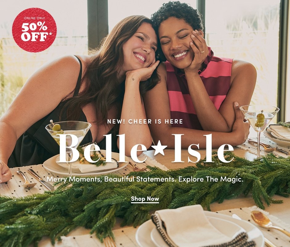 'Two smiling women sit close together at a holiday table decorated with green pine garland and white plates. One woman wears a black strappy dress, and the other wears a sleeveless red and pink striped top. Both hold martini glasses with olives. Large white text across the center reads NEW! CHEER IS HERE Belle★Isle Merry Moments, Beautiful Statements. Explore The Magic. Below it is a white button that reads Shop Now. In the upper left corner, a red textured circle with white text reads ONLINE ONLY 50% OFF*.'