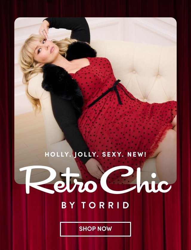 'A blonde woman reclines on a cream tufted couch wearing a red sleeveless dress patterned with small black hearts, trimmed in red lace, and tied at the waist with a black ribbon; she has on a black cardigan with a fluffy black collar. The background shows white paneled walls and a red theater-style curtain at the bottom. White text across the center reads HOLLY. JOLLY. SEXY. NEW! and Retro Chic BY TORRID, with a white rectangular SHOP NOW button at the bottom.'
