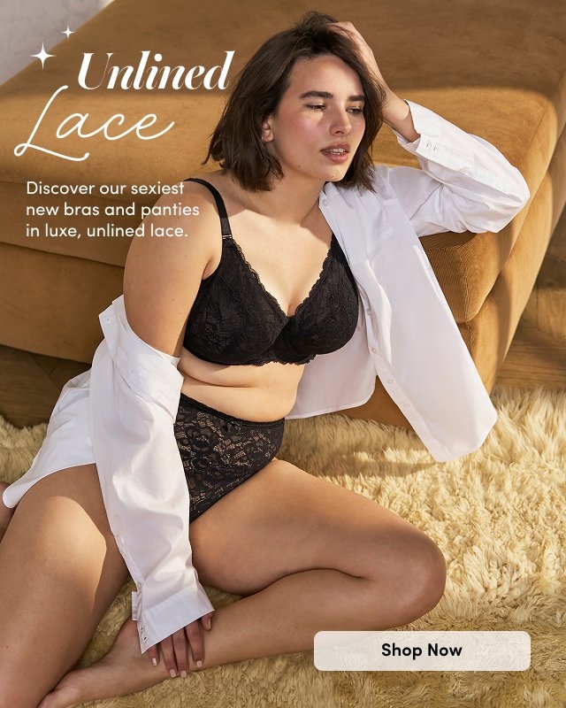 'A woman reclines on a tan sofa wearing a black unlined lace bra and matching high-waisted lace panties with a white button-down shirt draped open over her shoulders, sitting on a cream textured rug with a tan upholstered background. White script text at upper left reads Unlined Lace. Smaller white text below reads Discover our sexiest new bras and panties in luxe, unlined lace. A rounded light beige button below the text reads Shop Now. White decorative sparkle icons appear around the image.'
