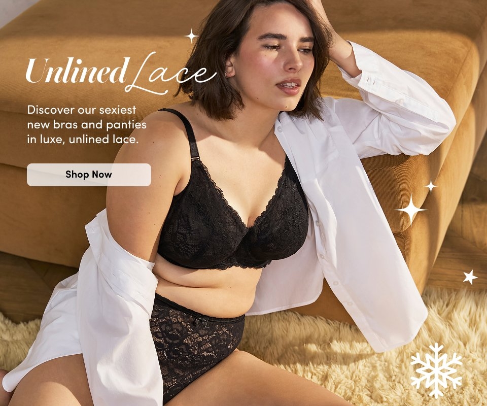 'A woman reclines on a tan sofa wearing a black unlined lace bra and matching high-waisted lace panties with a white button-down shirt draped open over her shoulders, sitting on a cream textured rug with a tan upholstered background. White script text at upper left reads Unlined Lace. Smaller white text below reads Discover our sexiest new bras and panties in luxe, unlined lace. A rounded light beige button below the text reads Shop Now. White decorative sparkle icons appear around the image.'