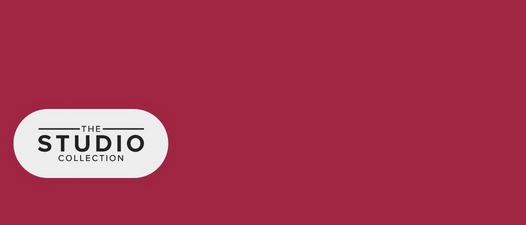 A horizontal banner with a deep pink to burgundy gradient background. On the left side, a white rounded rectangular pill-shaped button or badge contains black text arranged in three lines reading 'THE' (small, with decorative horizontal lines on either side), 'STUDIO' (large, bold letters), and 'COLLECTION' (small, in a condensed font).