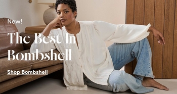 Woman models a white oversized blouse with light wash jeans while seated on the floor beside a leather sofa. Text reads New The Best Bombshell Shop Jeans.