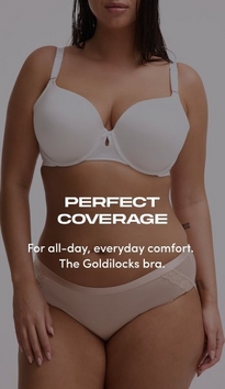 Model shown from chin to upper thigh against a light gray background, wearing a white t-shirt bra with molded cups, adjustable straps, and a small keyhole detail at center gore, paired with nude pink bikini panties with lace trim at the waistband. Model has long straight dark hair falling over one shoulder. White text overlay reads 'PERFECT COVERAGE' with subtext below reading 'For all-day, everyday comfort. The Goldilocks bra.'