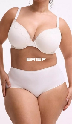 Model shown from neck to upper thighs against a light gray background, wearing a cream-colored t-shirt bra with molded cups, wide straps, and lace trim along the neckline, paired with matching cream high-waisted brief panties with a smooth finish. Model has curly hair visible at the top of the frame and hands resting on outer thighs. White text overlay reads 'BRIEF' across the midsection.