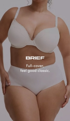 Model shown from neck to upper thighs against a light gray background, wearing a cream-colored t-shirt bra with molded cups, wide straps, and lace trim along the neckline, paired with matching cream high-waisted brief panties with a smooth finish. Model has curly hair visible at the top of the frame and hands resting on outer thighs. White text overlay reads 'BRIEF' with subtext below reading 'Full-cover, feel good classic.'