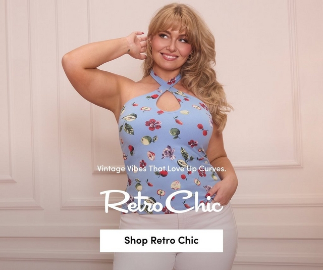 'A tall promotional banner with a soft blush pink paneled wall background and two upholstered chairs partially visible at the bottom. A plus-size model stands smiling with one hand raised near her ear and the other in her pocket. She wears a light blue fruit and floral print cross-neck halter top with a keyhole cutout and white pants, and has voluminous wavy blonde hair with bangs and gold hoop earrings. In the center in small white text reads New Just Bloomed. Below in large white script text reads Retro Chic, with smaller white text below reading Sexy-Sweet Spring Arrivals Are Waiting. At the bottom is a bold underlined white Shop Retro Chic link.'