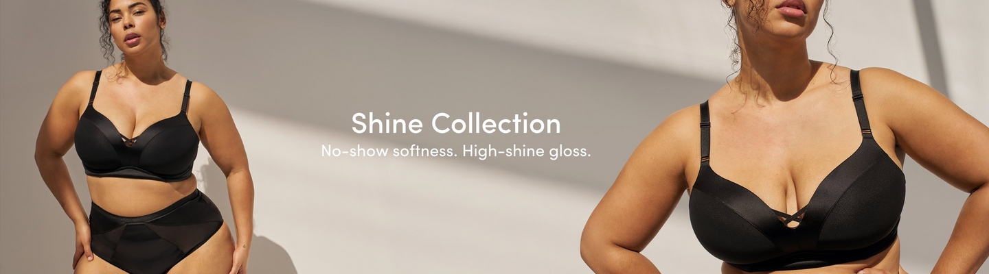 A promotional banner for the 'Shine Collection' with the tagline 'No-show softness. High-shine gloss.' in white text centered between two photos of the same woman against a warm gray background with soft light and shadow. She has dark curly hair and wears a black underwire bra with satin and mesh paneling and a small decorative cutout detail at the center front, paired with matching black high-waist briefs with geometric mesh and satin paneling. On the left she is shown from the waist up leaning slightly forward. On the right she is shown in a closer crop from the bust up with one hand on her hip.