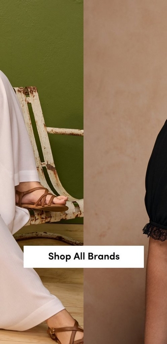 A split banner with a white 'Shop All Brands' button centered across two side-by-side cropped photos. On the left, a close detail shot shows the lower half of a woman in white wide-leg trousers and tan strappy flat sandals seated on a vintage distressed white metal chair against an olive green wall. On the right, a close cropped shot shows the torso of a woman in a black short-sleeve top with black lace trim at the sleeves against a warm taupe background.