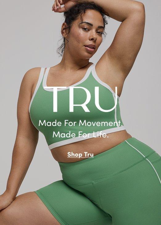 A model wears a ribbed sage green TRU activewear set consisting of a sports bra with white trim and matching high-waisted shorts. Large white overlay text reads "TRU Made For Movement. Made For Life." with a "Shop Tru" link below.