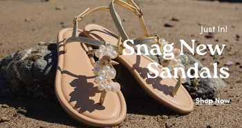 Gold T-strap sandals with decorative pearl and seashell embellishments resting on a rock in a beach setting. Text overlay reads: 'Just In! Snag New Sandals. Shop Now'.
