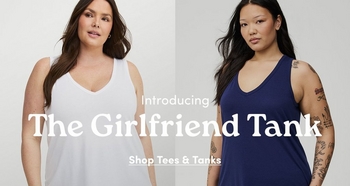 Two models side-by-side wearing white and navy blue V-neck tank tops. Central text overlay reads: 'Introducing The Girlfriend Tank' and 'Shop Tees & Tanks'.