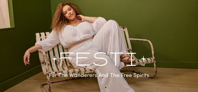 A promotional banner for 'Festi™' with the tagline 'For The Wanderers And The Free Spirits' in white text overlaid on the photo. A woman with voluminous curly light brown hair reclines on a vintage distressed white metal slatted outdoor chair against a dark olive green wall with light wood flooring. She wears a white long-sleeve cropped peasant-style top with a gathered neckline paired with white wide-leg drawstring trousers and tan strappy flat sandals, with one hand raised to her neck.