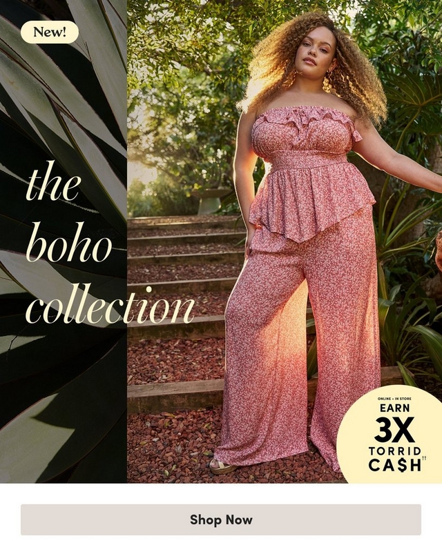 'Promotional banner for Torrid featuring the Boho Collection, set against a lush outdoor garden background with tropical plants and greenery. On the left side, large dark green agave leaves frame the edge of the image. Overlaid in cream-colored italic serif text is 'the boho collection', with a small cream rounded badge in the upper left reading 'New!' A plus-size woman with medium skin tone and long voluminous curly blonde-highlighted hair stands on stone steps surrounded by tropical foliage in warm golden sunlight. She wears a pink ditsy floral strapless ruffled crop top with a smocked bodice and peplum hem, paired with matching wide-leg pants, and gold drop earrings. In the lower right corner is a pale yellow circle badge with dark text reading 'Online + In Store Earn 3X Torrid Cash' with two daggers. At the bottom is a light gray rectangular button with bold dark text reading 'Shop Now'.'