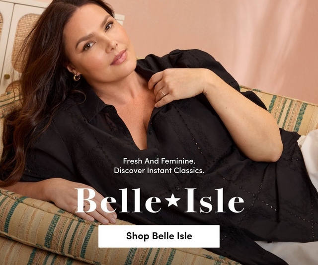 'Promotional banner for Torrid featuring Belle Isle against a soft peach background. A plus-size woman with light skin tone and long dark brown hair reclines on a striped woven sofa with green and tan tones, with one hand resting near her chest and the other on the cushion. She wears small gold hoop earrings, a ring, and a black short-sleeve button-front eyelet embroidered midi dress. Smaller white text reads 'Fresh And Feminine. Discover Instant Classics.' above large white serif text with a star graphic reading 'Belle Isle'. At the bottom is a white rectangular button with bold dark text reading 'Shop Belle Isle'.'