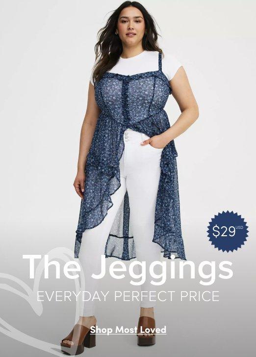 A promotional banner with a light gray background. A woman with dark hair pulled back stands facing forward with one hand in her pocket. She wears a sheer navy blue floral-print sleeveless duster over a white short-sleeve top and white fitted jeggings, with brown platform sandals. A blue circular badge on the right reads '$29' with a superscript asterisk. Overlaid white text in the lower portion reads 'The Jeggings' in large letters, with 'EVERYDAY PERFECT PRICE' in smaller text below it. At the bottom is a white rectangular button with dark text reading 'Shop Most Loved'.