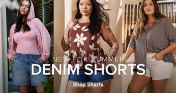 'Promotional banner for Torrid featuring three side-by-side photos of plus-size women wearing denim shorts in casual outdoor and indoor settings. From left to right: a woman with medium skin tone and long dark hair wears a pink ribbed zip-up hoodie and light wash denim bermuda shorts, standing near a window with visible shutters; a woman with medium skin tone and dark hair pulled back wears a brown and white floral peplum tank top and light wash denim cutoff shorts, with visible tattoos on both arms; and a woman with medium skin tone and shoulder-length dark hair wears an open gray and red plaid button-front shirt over a white top, paired with white denim shorts, with visible tattoos on her arm. Overlaid across the lower center in white text is 'NEW FOR SUMMER' above large bold white text reading 'DENIM SHORTS', with bold white underlined text below reading 'Shop Shorts'.