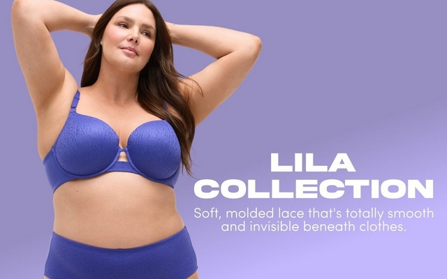 'Promotional banner for Torrid featuring the Lila Collection against a solid periwinkle purple background. A plus-size woman with light skin tone and long dark brown hair poses with both arms raised above her head, looking toward the camera. She is wearing a periwinkle blue lace-textured balconette bra with a small keyhole cutout detail at the center front, and matching high-waist briefs. On the right side, large bold white text reads 'LILA COLLECTION' with smaller white text below reading 'Soft, molded lace that's totally smooth and invisible beneath clothes.'.'