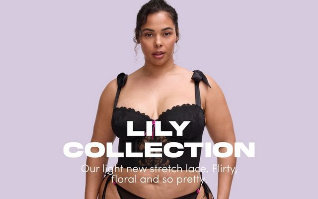 'A promotional banner for the Lily Collection featuring a plus-size woman with dark hair pulled up in a loose bun against a soft lavender background. She faces forward wearing a black stretch lace longline strapless bra with scalloped trim along the upper cups, a small hot pink bow at the center front, wide tie straps with black satin bow detail at the shoulders, and a sheer floral lace panel below the bust. A black lace thong with hot pink bow detail is partially visible at the bottom. Bold white text overlaid on the lower portion of the image reads 'LILY COLLECTION' with smaller white text below reading 'Our light new stretch lace. Flirty, floral and so pretty.''