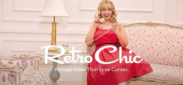 'Promotional banner for Torrid featuring Retro Chic, set in an elegant vintage-styled room with white paneled walls. A plus-size woman with light skin tone and long wavy blonde hair sits on a cream floral upholstered settee, laughing with an open expression and holding a cream-colored vintage rotary telephone handset to her ear. She is wearing a red polka dot fit-and-flare midi dress with a black ribbon belt at the waist and red nail polish. To her left is a small round side table with a cream rotary telephone base and a gold and cream table lamp, and a floral upholstered armchair is partially visible on the far left. Overlaid across the lower center in large white cursive script text is 'Retro Chic' with smaller white text below reading 'Vintage Vibes That Love Curves.'.'