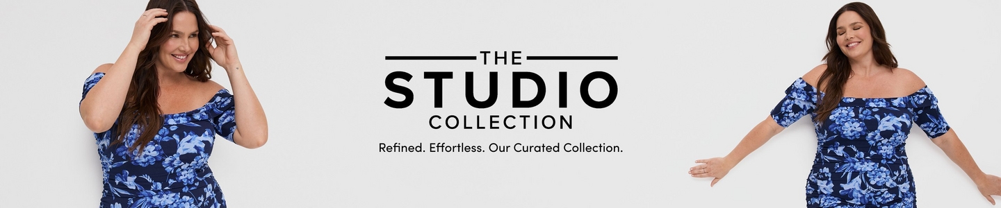 'Promotional banner for Torrid featuring The Studio Collection against a clean white background. The same plus-size woman with light skin tone and long dark brown hair appears twice, once on each side of the banner. On the left she poses smiling with one hand raised to her hair, and on the right she poses with eyes closed and arms slightly extended, smiling softly. In both photos she is wearing a navy blue and periwinkle floral off-the-shoulder ruched midi dress with short puff sleeves. In the center, bold dark text flanked by horizontal lines reads 'THE STUDIO COLLECTION' with smaller dark text below reading 'Refined. Effortless. Our Curated Collection.'.'