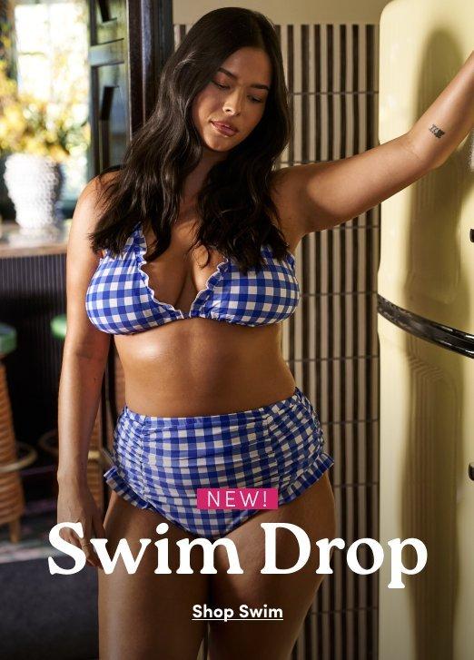 An advertisement featuring a woman in a blue and white checkered, gingham-patterned bikini. She has long, dark wavy hair and is posing indoors against a vintage-style refrigerator. The bikini top has ruffled edges, and the high-waisted bottoms feature ruching on the sides. Overlaid on the bottom of the image is the text "NEW! Swim Drop" in a bold white serif font, with a smaller link below that reads "Shop Swim."