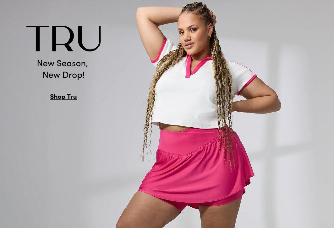 A promotional image for the brand TRU featuring a woman with long blonde braids posing in athletic wear against a neutral gray background. She is wearing a white short-sleeved cropped polo shirt with vibrant pink trim on the collar and sleeves, paired with a matching bright pink athletic skort that features a crossover waistband.