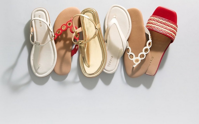 A mobile banner showcasing a row of summer sandals including white T-strap styles, tan sandals with red accents, gold metallic strappy sandals, white thong flip-flops, tan sandals with gold eyelets, and red woven slides, all set against a light grey background.
