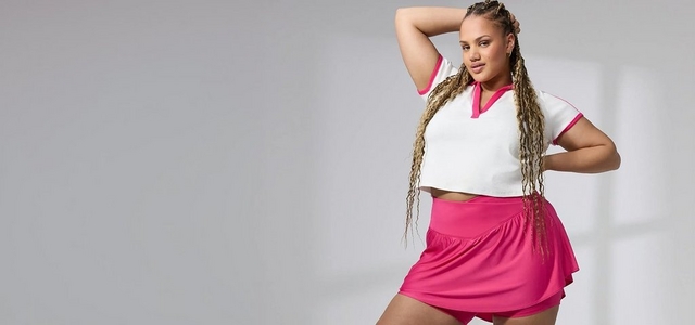 A model wearing a white polo shirt with pink trim and a matching pink athletic skort against a light gray background.