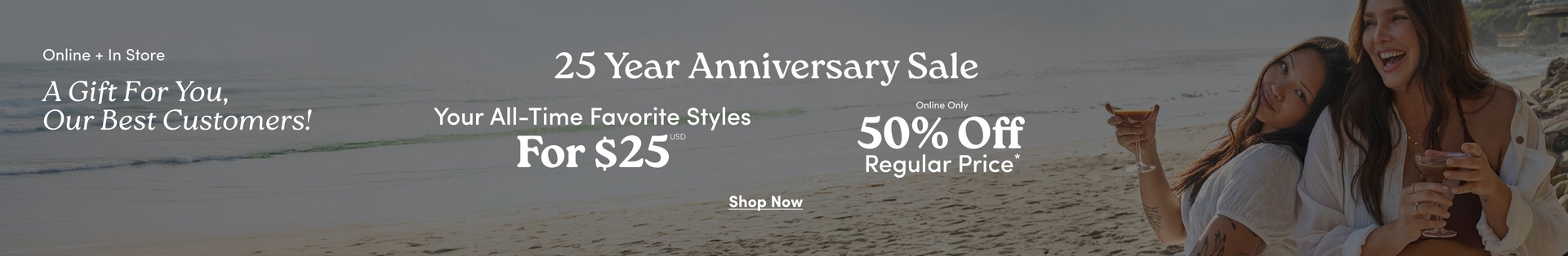 A wide horizontal promotional banner with a darkened beach scene background showing two women sitting together outdoors near the ocean, both with long dark hair wearing white outfits, one laughing and holding a drink. White text on the left reads 'Online + In Store' and 'A Gift For You, Our Best Customers!' in italic script. Centered white text reads '25 Year Anniversary Sale', then side by side: 'Your All-Time Favorite Styles For $25 USD*' on the left and 'Online Only 50% Off Regular Price*' on the right. At the bottom center is underlined white text reading 'Shop Now'.