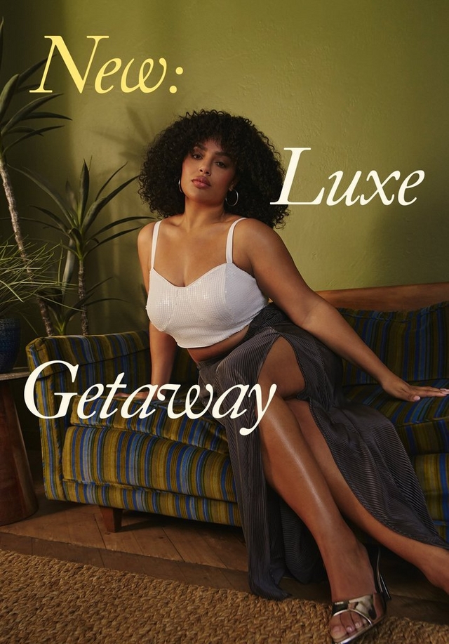 A tall vertical promotional banner showing the same woman from the center panel of Image 1, now featured more prominently. She has voluminous dark curly hair and gold hoop earrings and sits on a green and blue striped sofa against an olive green wall, with a tall potted plant in the background and a woven rug on the floor. She wears a white textured crop bralette and a dark gray pleated maxi skirt with a front slit, with silver strappy heeled sandals. Overlaid text reads 'New:' in yellow italic script in the upper left, 'Luxe' in large white italic script on the right, and 'Getaway' in large white italic script at the lower left.