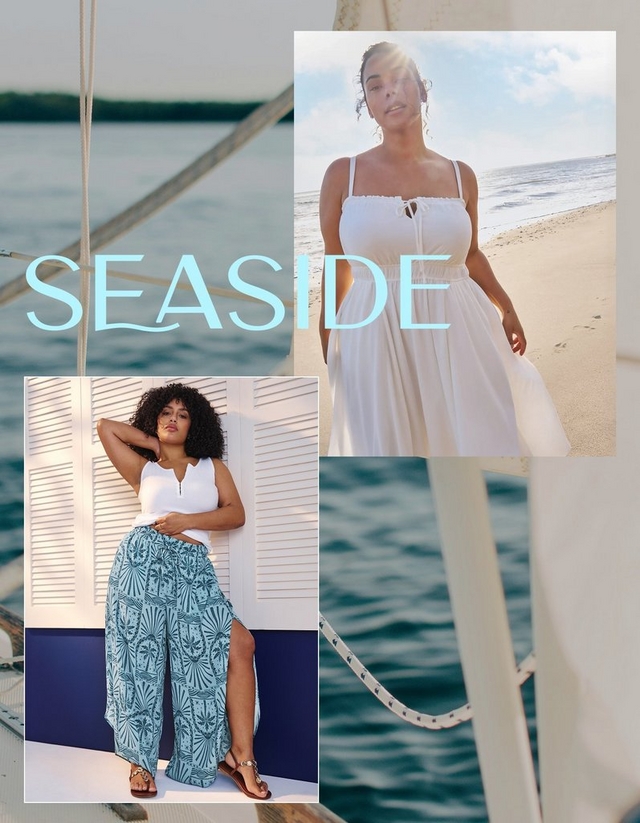 A vertical collage-style promotional banner with a blurred sailboat deck and calm blue ocean as the background. Large light blue text in the center reads 'SEASIDE'. Two overlapping photo panels are arranged on the banner. The top right panel shows a woman with dark curly hair standing on a sandy beach in bright sunlight, wearing a white smocked spaghetti-strap maxi dress with a keyhole tie detail at the chest and a full gathered skirt. The bottom left panel shows a woman with voluminous curly hair posing against white louvered shutters in front of a navy blue wall, wearing a white sleeveless V-neck top and wide-leg teal geometric-printed pants with a side slit, paired with strappy embellished sandals.