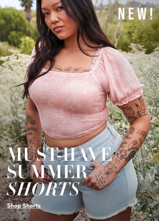 Promotional image featuring a model outdoors wearing a light pink smocked puff sleeve crop top with light wash denim shorts. Text reads “NEW! Must-Have Summer Shorts” with “Shop Shorts” below.