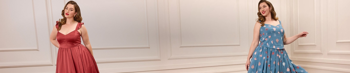 Wide promotional banner featuring two models with pin-up style wavy brown hair and red lipstick against a white paneled wall. Left model wears a red and white gingham fit-and-flare dress with ruffle shoulder straps and a sweetheart neckline. Right model wears a blue fit-and-flare dress with a hot air balloon print, sweetheart neckline, and a full pleated skirt.