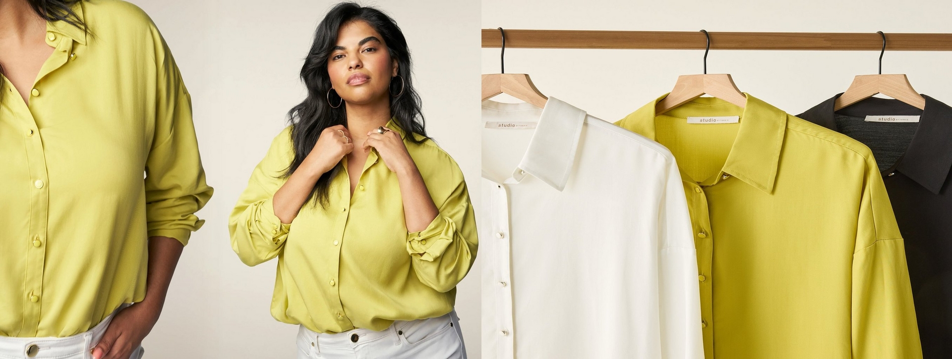 A wide horizontal banner split into two sections against a warm cream background. On the left, two overlapping images show close-up detail of a chartreuse yellow-green satin button-front shirt, and a woman with long dark wavy hair posing with both hands raised to her collar, wearing the same shirt with the sleeves rolled up, paired with white jeans. She wears large gold hoop earrings and rings. On the right, three button-front shirts in the same style hang on wooden hangers on a wooden clothing rod, shown in white, chartreuse yellow-green, and black, each with a small 'studio' label tag visible at the collar.