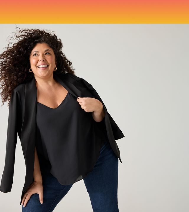 Tiff, Torrid Casting Call 2025 Winner from Los Angeles, California, laughing as the wind blows through her curly hair, wearing a black blazer over a black top.
