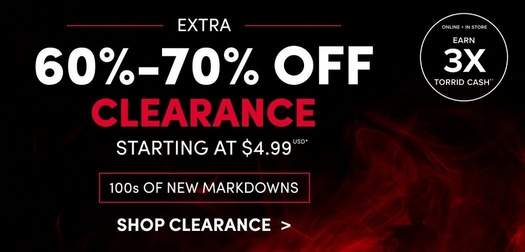 A wide promotional banner with a dark background and red smoke graphic. White text reads 'EXTRA' followed by large white text reading '60%-70% OFF' and large red text reading 'CLEARANCE' with white text below reading 'STARTING AT $4.99 USD*' A red-outlined rectangular badge reads '100s OF NEW MARKDOWNS' and a white text link reads 'SHOP CLEARANCE >' A white circle badge in the upper right reads 'ONLINE + IN STORE EARN 3X TORRID CASH**'