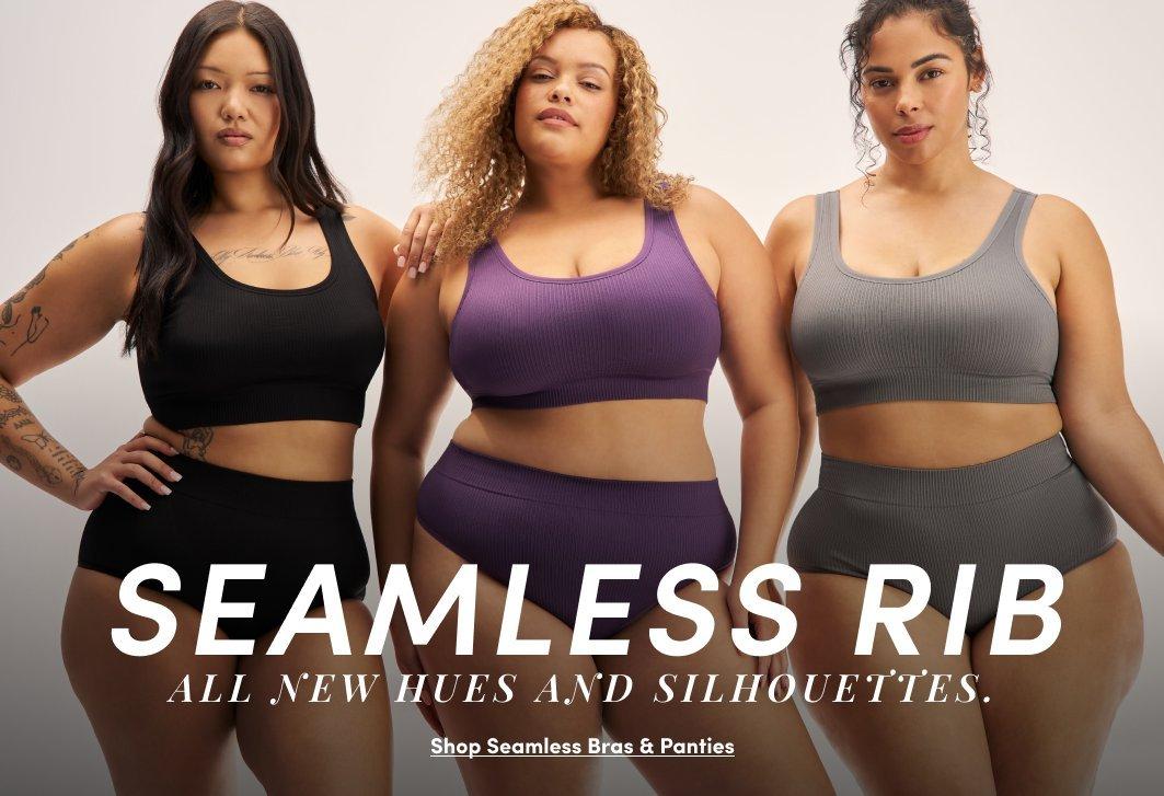 A promotional banner with a warm gray background showing three women standing together. The woman on the left has long dark hair and wears a dark navy blue seamless ribbed sports bra and matching high-waist shorts. The woman in the center has curly light brown hair and wears a mauve purple seamless ribbed sports bra and matching high-waist leggings. The woman on the right has long dark hair pulled back and wears a light gray seamless ribbed sports bra and matching high-waist shorts. White text overlay reads 'SEAMLESS RIB' in large bold letters with smaller text reading 'ALL NEW HUES AND SILHOUETTES.' and an underlined link reading 'Shop Seamless Bras & Panties.'
