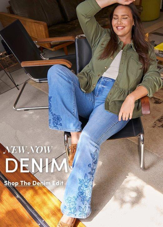 Model seated in a modern chair wearing an olive green utility jacket over a striped top, paired with light wash floral embroidered flare jeans and tan loafers. Text reads, “New Now Denim,” with a “Shop The Denim Edit” call to action.