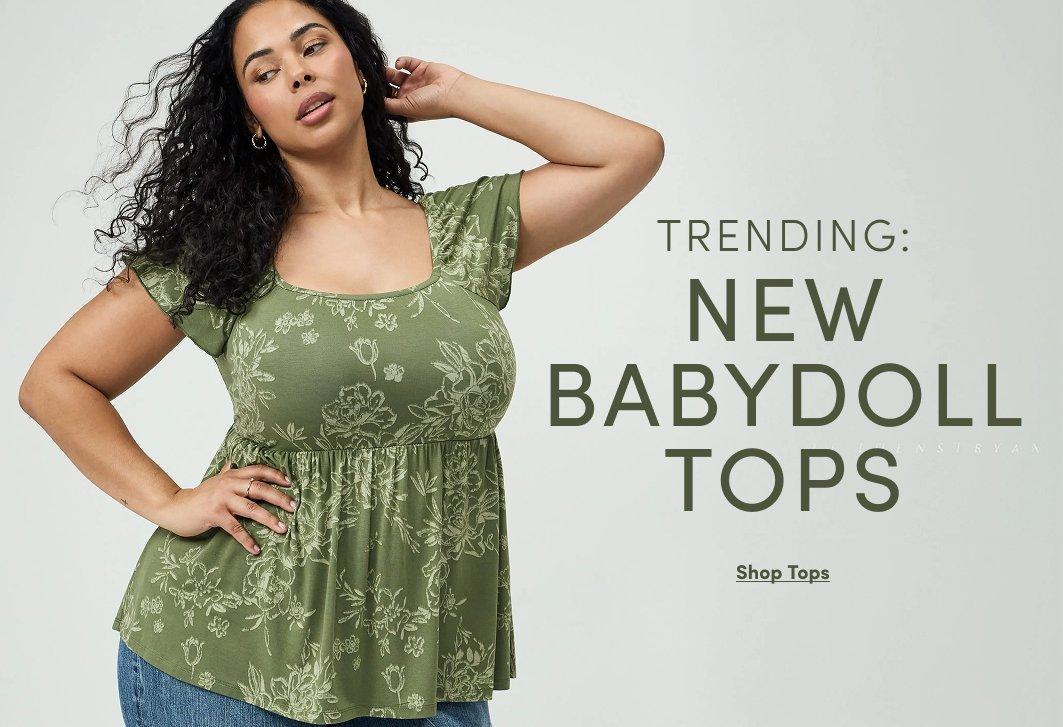 Model wearing an olive green floral print babydoll top with short flutter sleeves and blue jeans. Text reads, “Trending: New Babydoll Tops,” with a “Shop Tops” call to action.