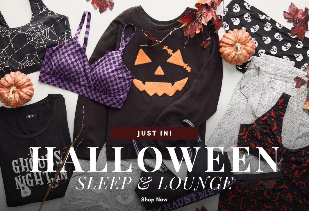 Flat lay of Halloween-themed sleepwear and lounge pieces, including graphic tees, a jack-o'-lantern sweatshirt, a purple checkered bralette, skull-print shorts, spiderweb-print top, joggers, and matching panties, styled with pumpkins and fall leaves. Text reads, “Just In! Halloween Sleep & Lounge.” with a “Shop Now” call to action.