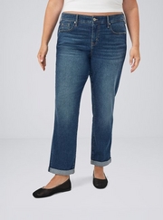 Cropped photo showing a woman's lower body against a plain light gray background, wearing a white cropped top with dark wash straight leg jeans featuring cuffed hems, paired with black flat shoes with a mesh texture. 